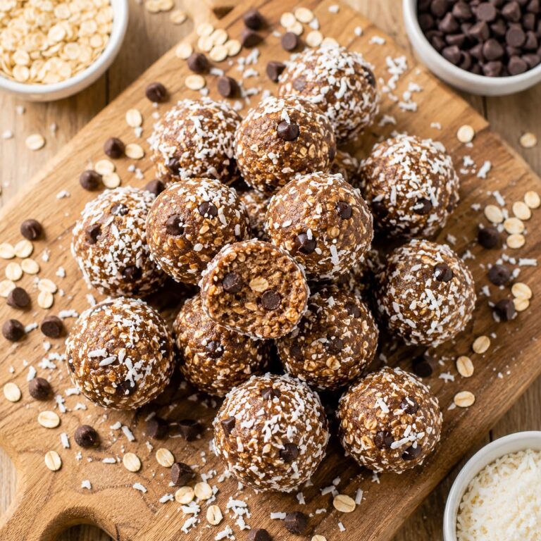 No-bake energy balls rolled in coconut flakes with chocolate chips and oats on a wooden board