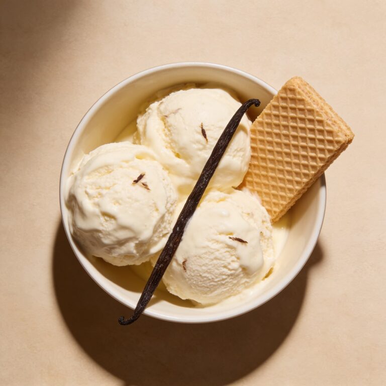 No-churn vanilla ice cream scoops in a bowl with vanilla bean specks and a wafer cookie